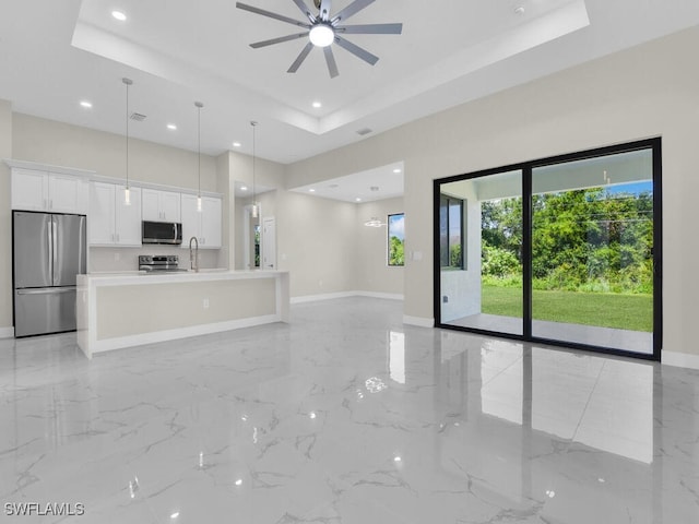 1304 Williams Ave, Lehigh Acres, FL 33972 - unfurnished living room with a tray ceiling, light marble finish flooring, a ceiling fan, and recessed lighting