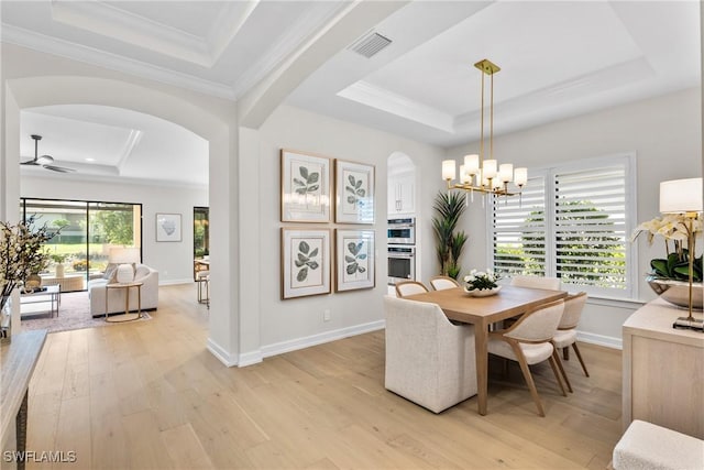 8834 Vaccaro Ct, Naples, FL 34119 - dining area featuring a tray ceiling, arched walkways, light wood finished floors, a chandelier, and ornamental molding