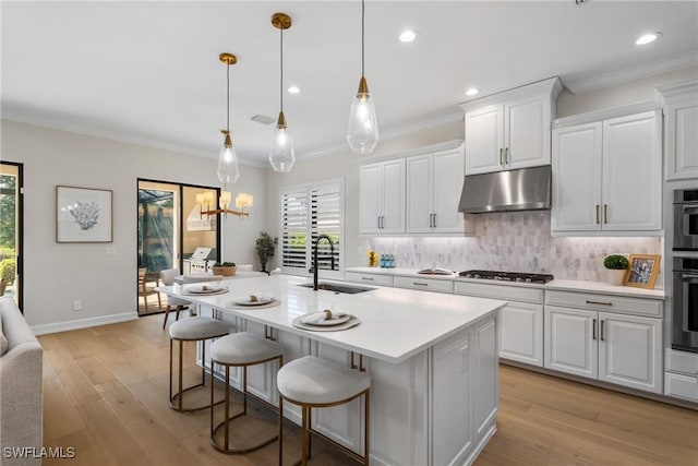 8834 Vaccaro Ct, Naples, FL 34119 - kitchen featuring under cabinet range hood, light countertops, gas cooktop, tasteful backsplash, and ornamental molding