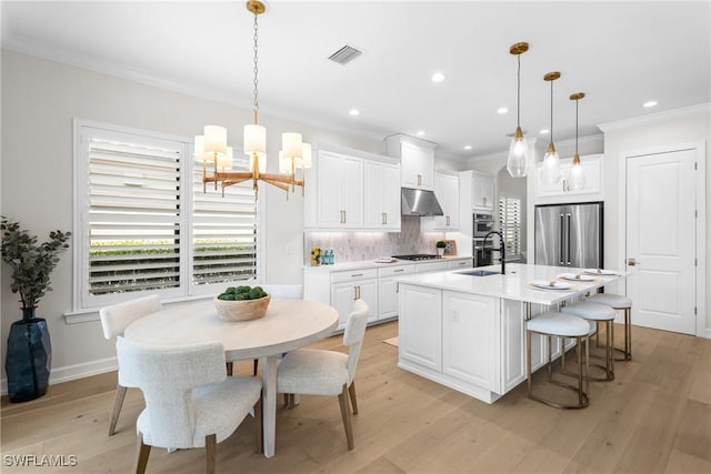 8834 Vaccaro Ct, Naples, FL 34119 - kitchen featuring high end fridge, a chandelier, under cabinet range hood, gas cooktop, and crown molding