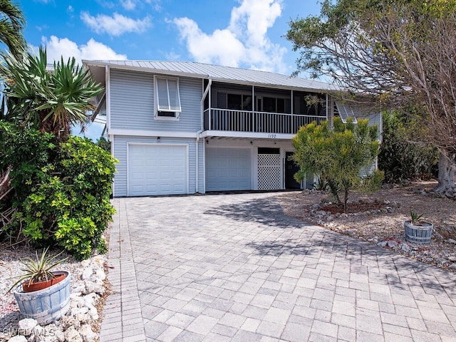 1132 Bond Ct, Marco Island, FL 34145 - view of front of house with decorative driveway, a garage, a metal roof, and a sunroom