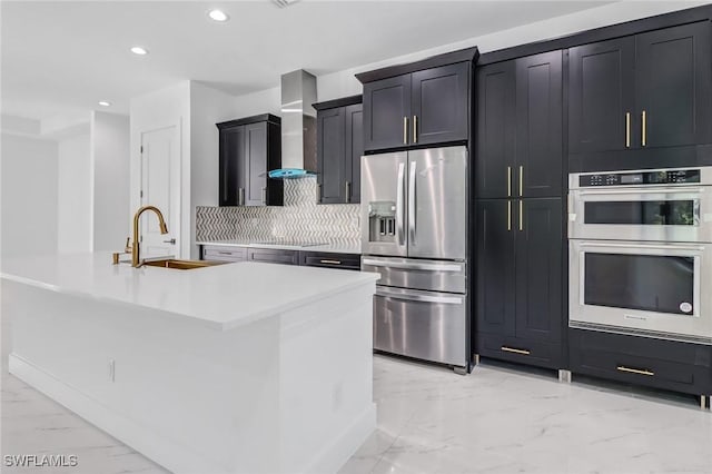 491 9th St SW, Naples, FL 34117 - kitchen featuring appliances with stainless steel finishes, light marble finish flooring, recessed lighting, decorative backsplash, and wall chimney exhaust hood