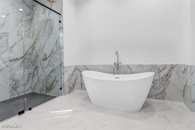 491 9th St SW, Naples, FL 34117 - bathroom with marble tiled floors, a marble finish shower, tile walls, a soaking tub, and a wainscoted wall