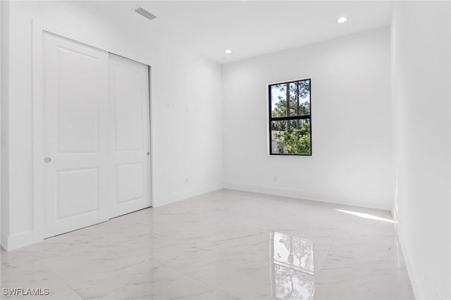 491 9th St SW, Naples, FL 34117 - unfurnished bedroom with light marble finish floors, recessed lighting, and a closet