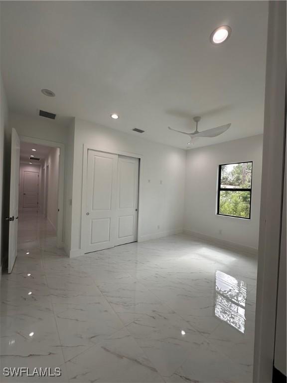 491 9th St SW, Naples, FL 34117 - unfurnished bedroom with light marble finish flooring, a closet, recessed lighting, and a ceiling fan