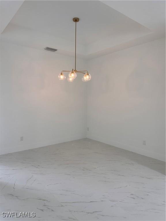 491 9th St SW, Naples, FL 34117 - spare room featuring a raised ceiling, a chandelier, and light marble finish flooring