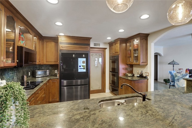 1920 Virginia Ave Unit 1102, Fort Myers, FL 33901 - kitchen with black appliances, arched walkways, dark stone counters, tasteful backsplash, and brown cabinets