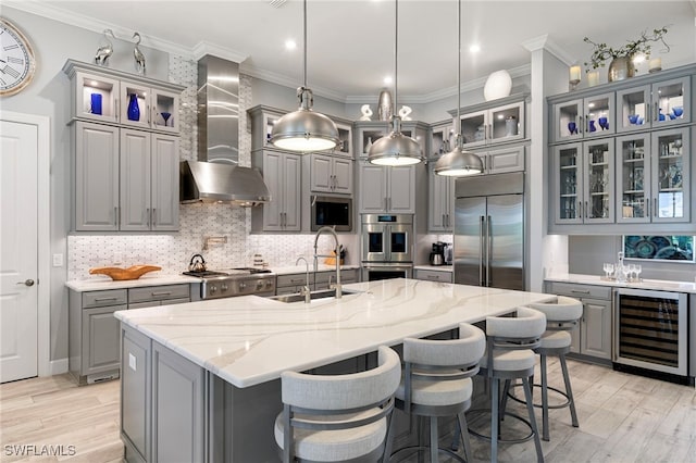 11699 Caleri Ct, Fort Myers, FL 33913 - kitchen with beverage cooler, gray cabinets, stainless steel appliances, wall chimney range hood, and an island with sink