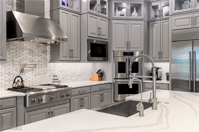 11699 Caleri Ct, Fort Myers, FL 33913 - kitchen featuring wall chimney exhaust hood, gray cabinetry, stainless steel appliances, and backsplash