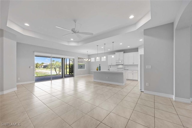 14601 Tropical Dr, Naples, FL 34114 - unfurnished living room featuring a tray ceiling, ceiling fan, recessed lighting, light tile patterned floors, and a chandelier