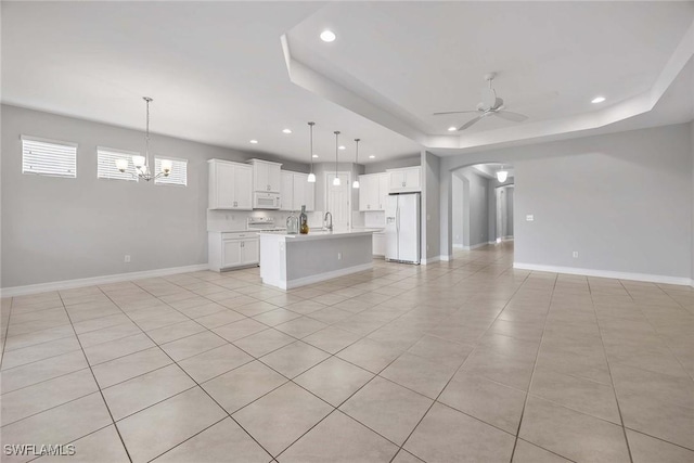 14601 Tropical Dr, Naples, FL 34114 - unfurnished living room with a ceiling fan, recessed lighting, arched walkways, a tray ceiling, and a chandelier