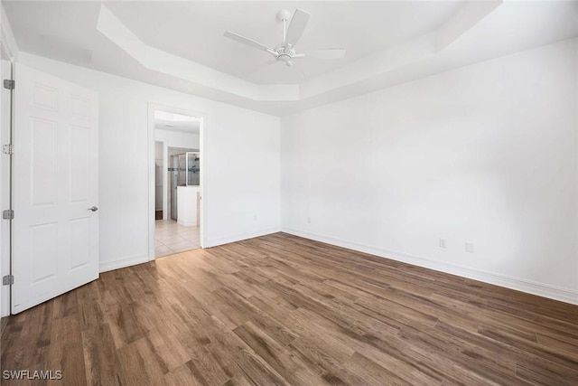 14601 Tropical Dr, Naples, FL 34114 - unfurnished bedroom with a tray ceiling, wood finished floors, a ceiling fan, and connected bathroom