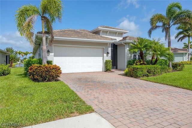 14601 Tropical Dr, Naples, FL 34114 - view of front of house with a front yard, an attached garage, decorative driveway, and stucco siding