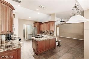 4238 Golfair Ln, North Port, FL 34288 - kitchen featuring vaulted ceiling, a ceiling fan, refrigerator, brown cabinets, and decorative light fixtures