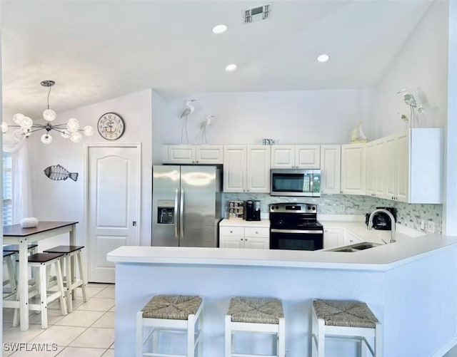 1958 Terrazzo Ln, Naples, FL 34104 - kitchen featuring appliances with stainless steel finishes, a peninsula, light tile patterned flooring, a kitchen breakfast bar, and recessed lighting
