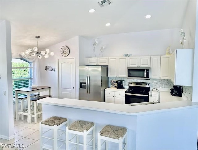1958 Terrazzo Ln, Naples, FL 34104 - kitchen featuring appliances with stainless steel finishes, backsplash, a peninsula, light tile patterned flooring, and light countertops