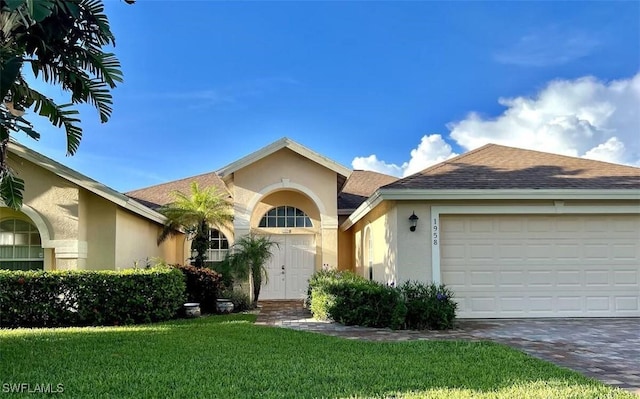 1958 Terrazzo Ln, Naples, FL 34104 - view of front of home featuring stucco siding, a front yard, driveway, an attached garage, and a shingled roof