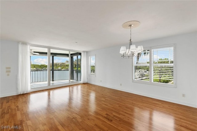 420 Cove Tower Dr Unit 304, Naples, FL 34110 - empty room featuring a chandelier, plenty of natural light, wood finished floors, and a water view