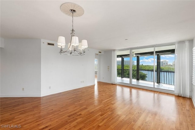 420 Cove Tower Dr Unit 304, Naples, FL 34110 - empty room featuring a chandelier, floor to ceiling windows, light wood-style flooring, and a water view