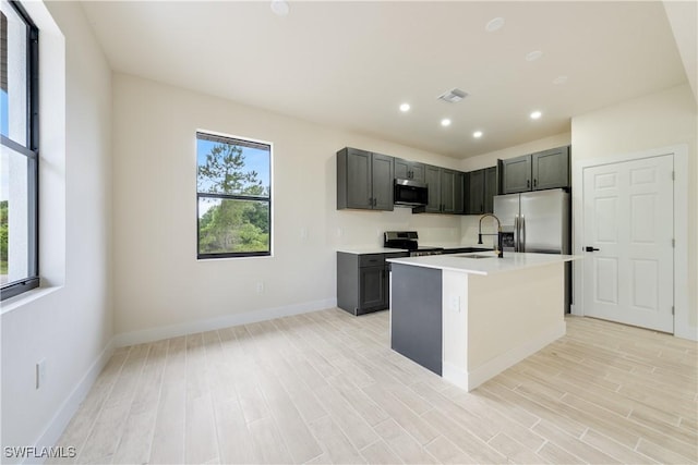 2701 53rd St W, Lehigh Acres, FL 33971 - kitchen featuring appliances with stainless steel finishes, light countertops, light wood-type flooring, a center island with sink, and recessed lighting