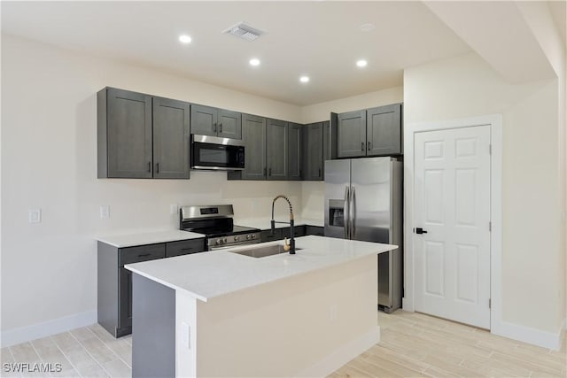 2701 53rd St W, Lehigh Acres, FL 33971 - kitchen with stainless steel appliances, light wood-style floors, light countertops, a center island with sink, and recessed lighting