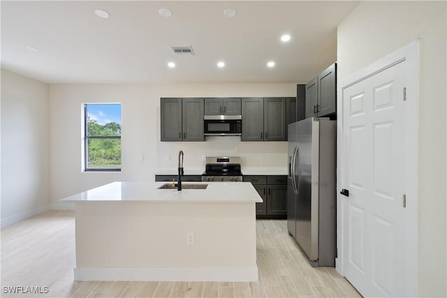2703 54th St W, Lehigh Acres, FL 33971 - kitchen with appliances with stainless steel finishes, an island with sink, light countertops, recessed lighting, and light wood-type flooring