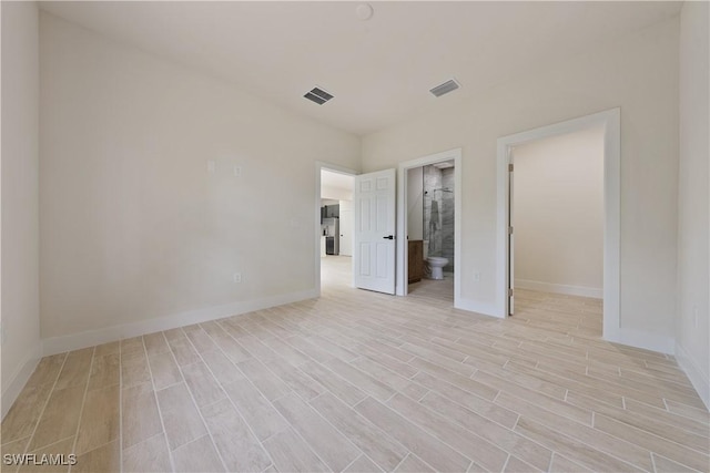 2703 54th St W, Lehigh Acres, FL 33971 - unfurnished bedroom featuring light wood-style flooring, a spacious closet, and connected bathroom