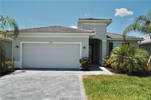 2445 Orchard St, Naples, FL 34120 - view of front facade with stucco siding, an attached garage, a tiled roof, and decorative driveway