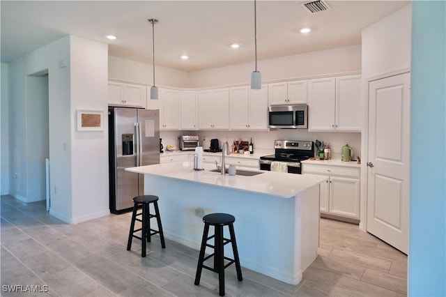 2445 Orchard St, Naples, FL 34120 - kitchen featuring stainless steel appliances, a breakfast bar, white cabinetry, decorative light fixtures, and recessed lighting