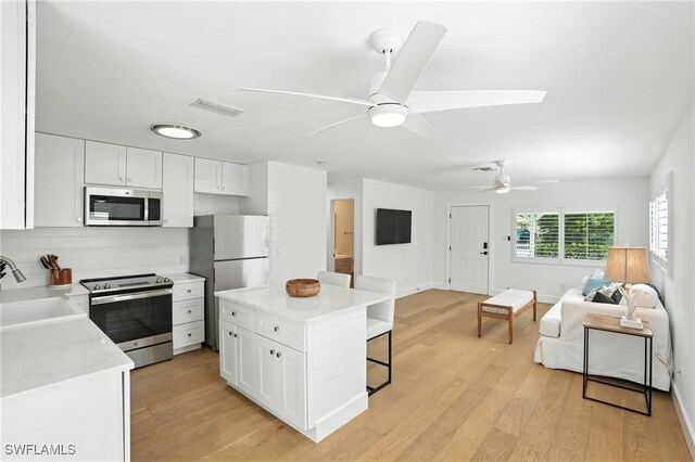 1324 Highlands Dr, Naples, FL 34103 - kitchen with stainless steel appliances, open floor plan, a kitchen breakfast bar, ceiling fan, and white cabinets