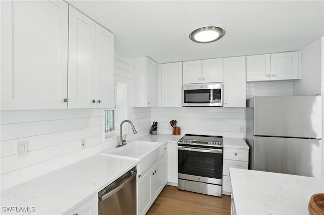 1324 Highlands Dr, Naples, FL 34103 - kitchen with appliances with stainless steel finishes, white cabinets, light wood-style floors, and light stone countertops
