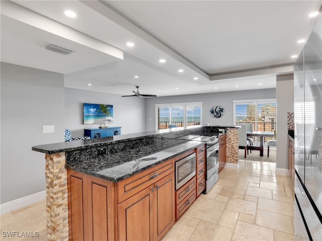 1100 N Collier Blvd Unit 920, Marco Island, FL 34145 - kitchen with stainless steel appliances, brown cabinets, dark stone counters, recessed lighting, and stone tile floors