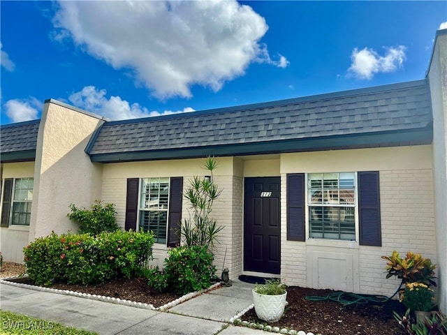 6300 S Pointe Blvd Unit 312, Fort Myers, FL 33919 - entrance to property featuring brick siding, a shingled roof, and mansard roof