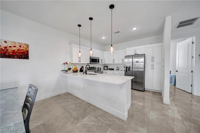 2607 4th St SW, Lehigh Acres, FL 33976 - kitchen featuring stainless steel appliances, a peninsula, light countertops, white cabinetry, and decorative light fixtures