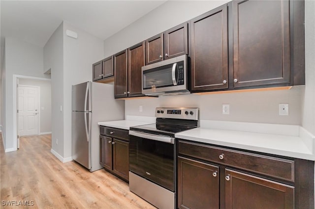 1492 Schenley St, Port Charlotte, FL 33952 - kitchen with stainless steel appliances, light wood-style floors, dark brown cabinetry, and light countertops