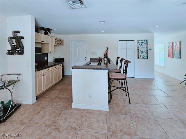 2640 4th Ave NE, Naples, FL 34120 - kitchen featuring light tile patterned flooring, a breakfast bar area, recessed lighting, cream cabinetry, and an island with sink