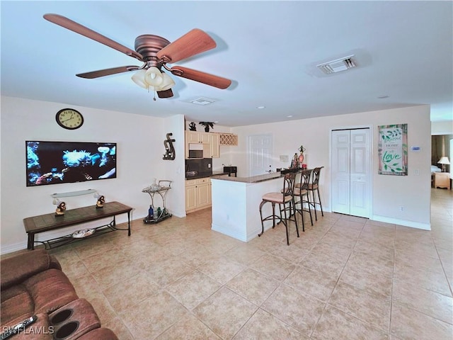 2640 4th Ave NE, Naples, FL 34120 - kitchen featuring a kitchen bar, light tile patterned floors, ceiling fan, a peninsula, and dark countertops