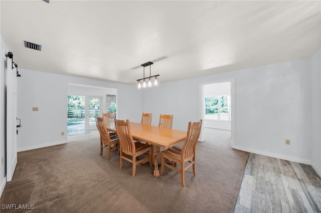 19350 Meredith Rd, North Fort Myers, FL 33917 - dining area featuring a barn door, healthy amount of natural light, a chandelier, and wood finished floors
