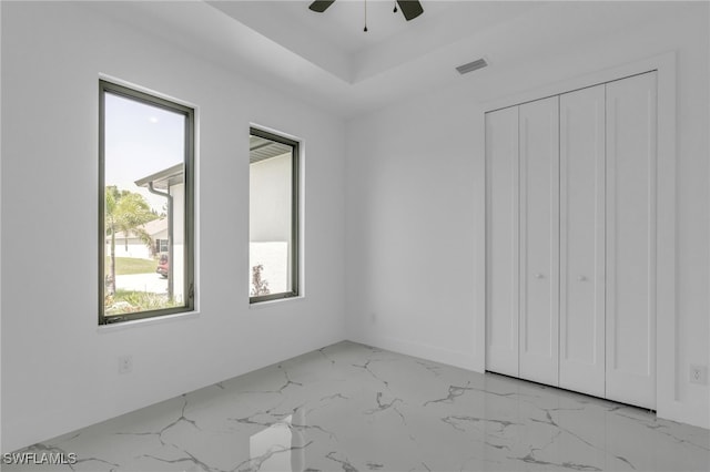 834 NW 2nd St, Cape Coral, FL 33993 - unfurnished bedroom featuring light marble finish flooring, a closet, ceiling fan, and a tray ceiling