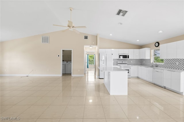 3206 8th St SW, Lehigh Acres, FL 33976 - kitchen with white appliances, washer and clothes dryer, open floor plan, a kitchen island, and tasteful backsplash