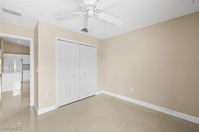 3206 8th St SW, Lehigh Acres, FL 33976 - unfurnished bedroom with a closet, white fridge with ice dispenser, a ceiling fan, and light tile patterned floors
