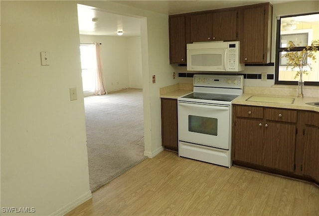 4807 6th St W, Lehigh Acres, FL 33971 - kitchen with white appliances, light countertops, light wood finished floors, and light colored carpet