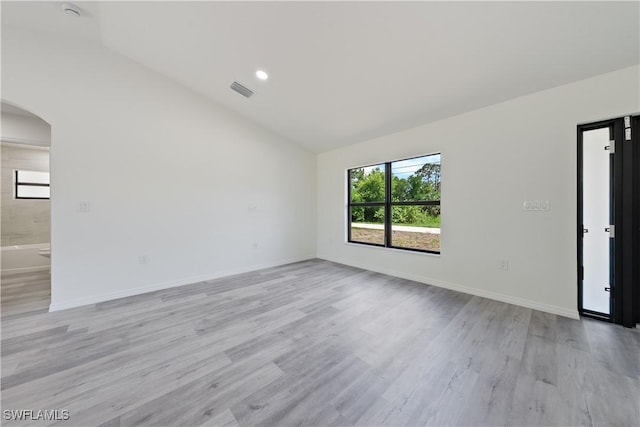 2912 8th St W, Lehigh Acres, FL 33971 - spare room featuring vaulted ceiling, arched walkways, and light wood finished floors