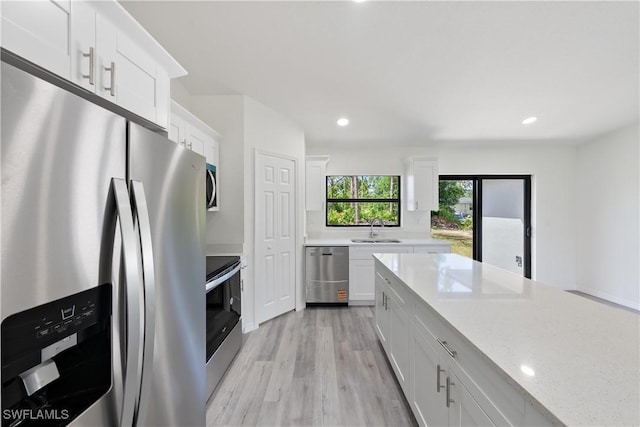 2912 8th St W, Lehigh Acres, FL 33971 - kitchen featuring stainless steel appliances, white cabinetry, light wood-type flooring, recessed lighting, and light stone counters
