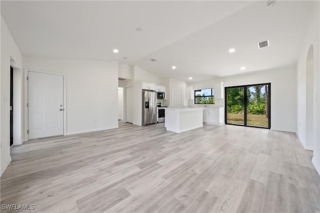 2912 8th St W, Lehigh Acres, FL 33971 - unfurnished living room featuring vaulted ceiling, light wood-type flooring, arched walkways, and recessed lighting