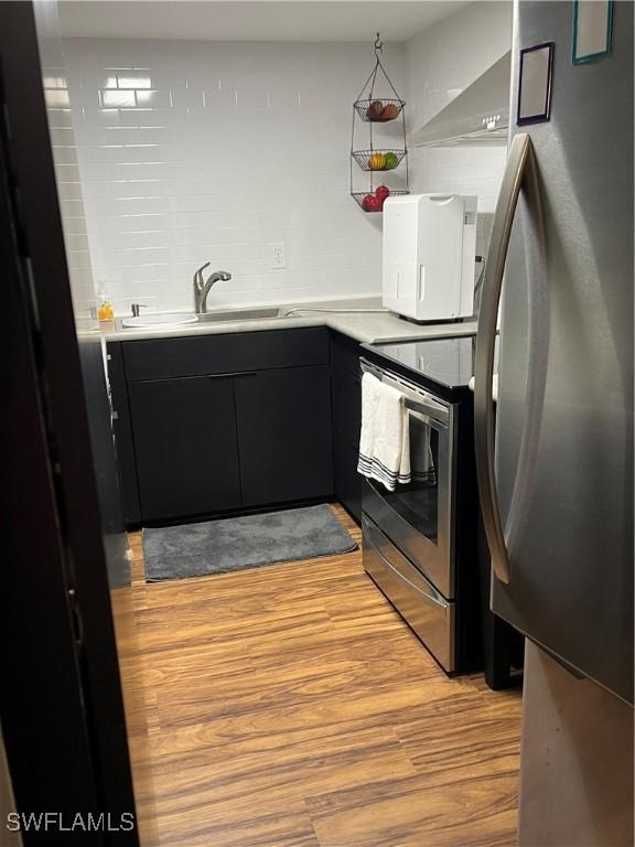 1900 Clifford St Unit 606, Fort Myers, FL 33901 - kitchen with stainless steel appliances, dark cabinetry, light wood-style floors, and light countertops