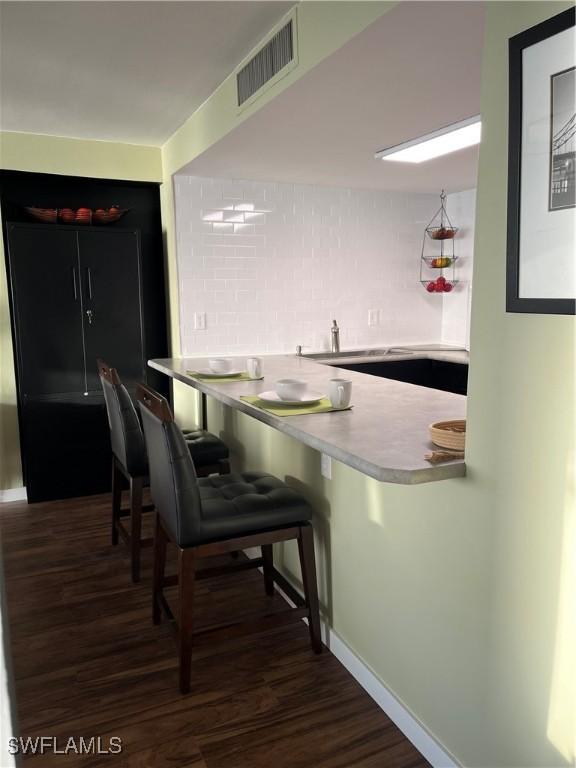 1900 Clifford St Unit 606, Fort Myers, FL 33901 - kitchen featuring wood finished floors, tasteful backsplash, a kitchen breakfast bar, and a peninsula