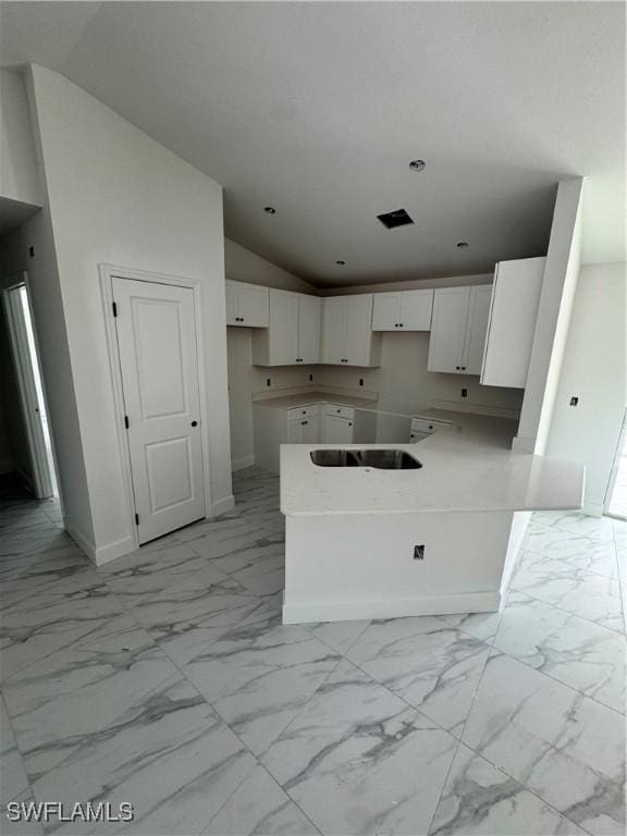 712 Oakridge Ave S, Lehigh Acres, FL 33974 - kitchen with lofted ceiling, light marble finish flooring, white cabinetry, and a peninsula