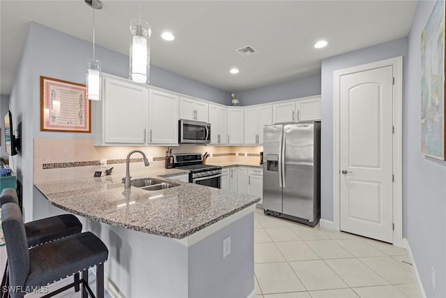 20147 Torch Key Way, Estero, FL 33928 - kitchen featuring appliances with stainless steel finishes, a peninsula, light stone counters, white cabinetry, and light tile patterned floors