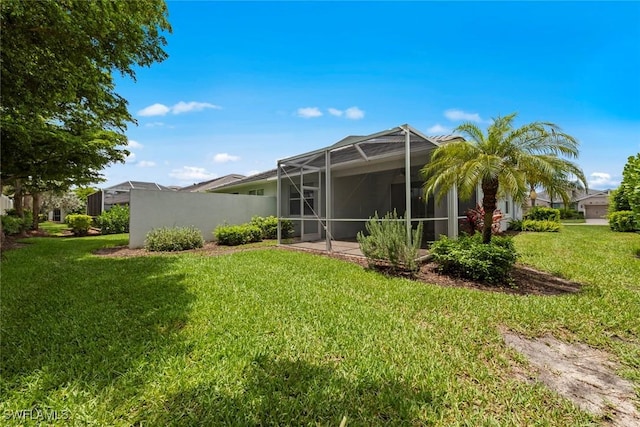 20147 Torch Key Way, Estero, FL 33928 - rear view of property featuring a lawn, glass enclosure, and stucco siding